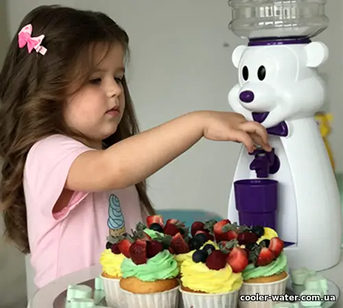 Дівчинка наповнює стаканчик із білого дитячого кулера